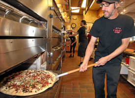 Pizza My Heart manager Brian Leopole pulls a DeLex pizza from the oven at the 41st Avenue restaurant.  (Dan Coyro -- Santa Cruz Sentinel)